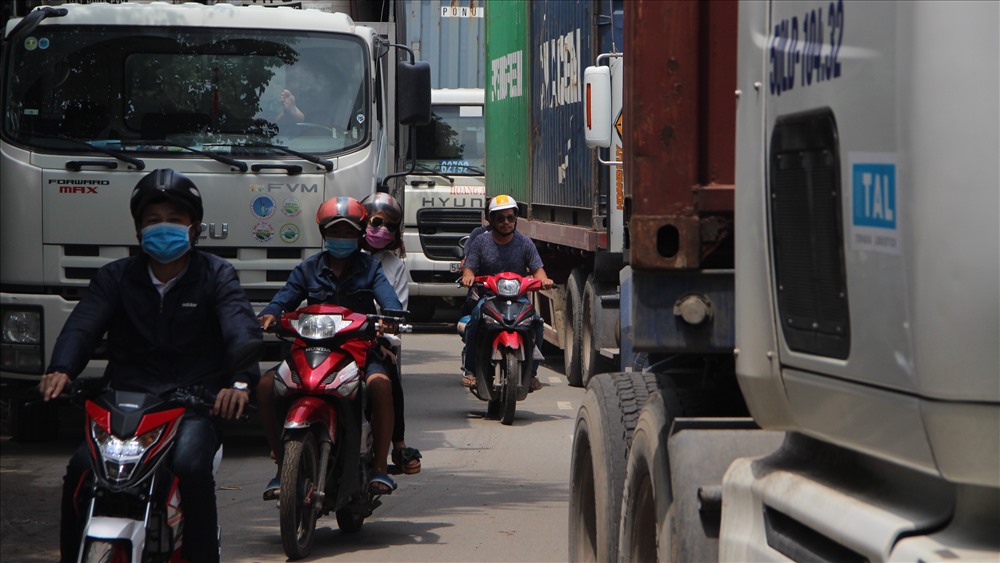 Người dân luồn lách nguy hiểm qua đầu xe tải lớn để di chuyển.