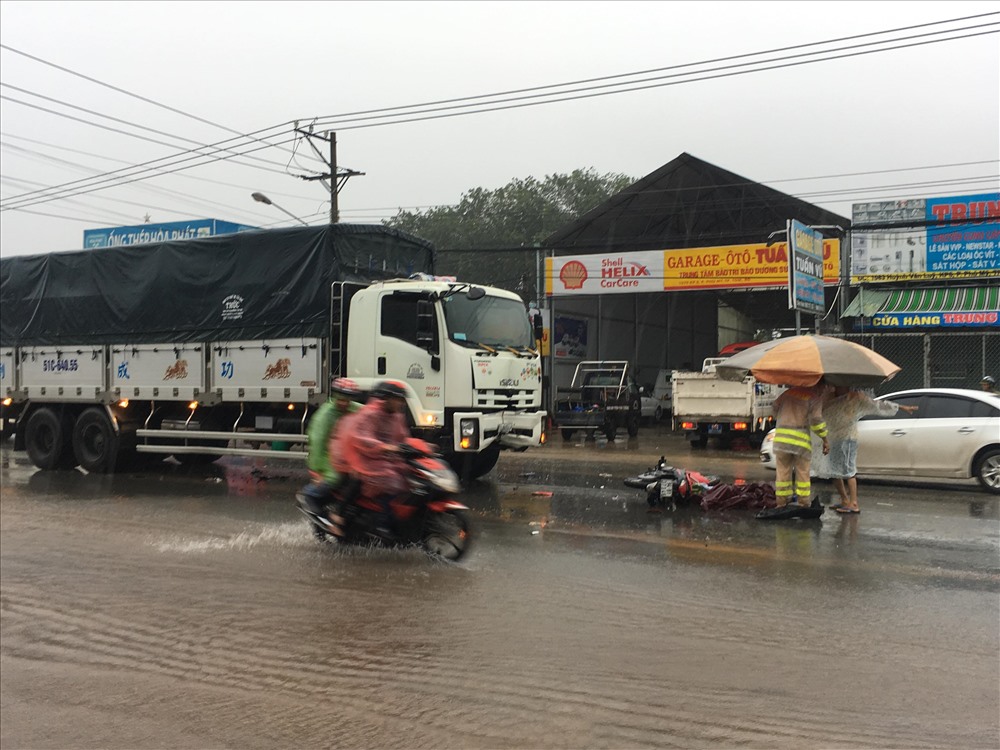 Người đàn ông bị tai nạn tử vong dưới trời mưa bão, người dân mang ô ra che thi thể.