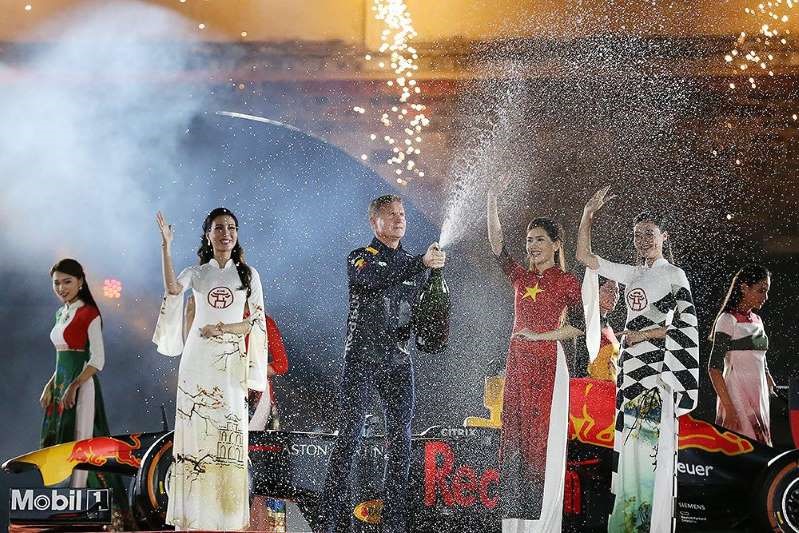 Hình ảnh đẹp của tay đua từng 13 lần vô địch các chặng đua F1 tái hiện lại màn ăn mừng chiến thắng truyền thống của nhà vô địch F1 bên sự xuất hiện dịu dàng của những tà áo dài dân tộc