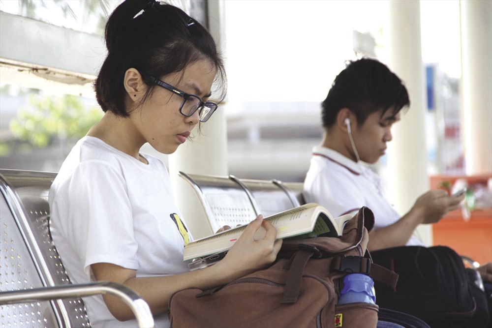 Giới trẻ đi xe buýt ngồi đọc sách tại nhà chờ.