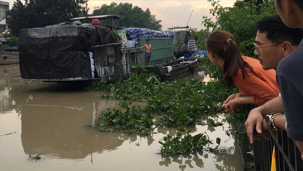 Nam thanh niên khống chế một phụ nữ cố thủ trong thuyền. Người thân đứng bên ngoài lo lắng.