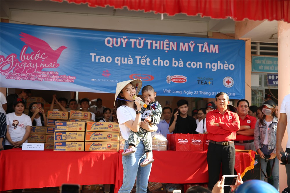 Nữ diễn viên gần gũi và thân thiện khi vừa giao lưu với bà con vừa bế em bé trên tay.