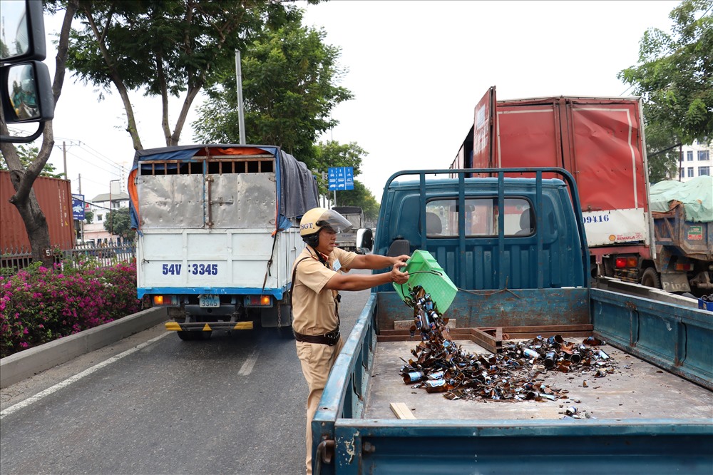 CSGT thu dọn mảnh vỡ thủy tinh từ hàng chục thùng bia rơi xuống QL1 trưa nay. Ảnh: T.S